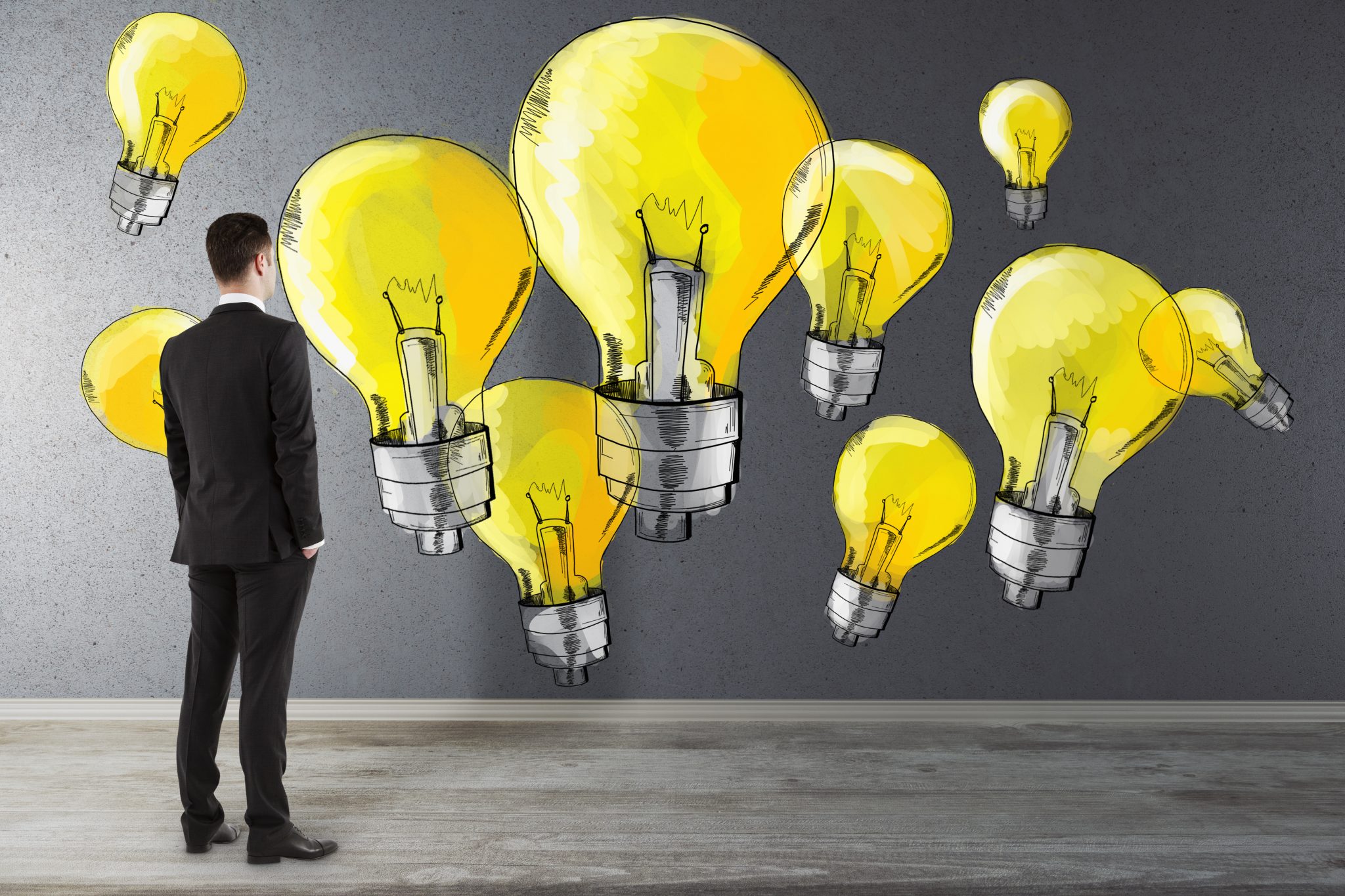 Symbolfoto für Kreativität und Design Thinking: Mann steht vor einer Wand mit gelben Glühbirnen im Comic-Stil