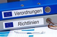 Zwei aufeinander gestapelte Odner sind mit dem EU-Logo und den Aufschriften Verordnungen und Richtlinien etikettiert