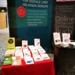 Der Stand des Walhalla Verlages mit einer Auswahl an Büchern auf zwei Tischen vor einem großen Werbebanner